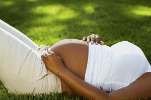 Gravid kvinde der ligger på grøn eng